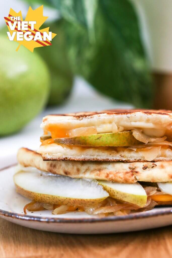 Vegan grilled cheese sandwich with pears and a plant blurred in the background
