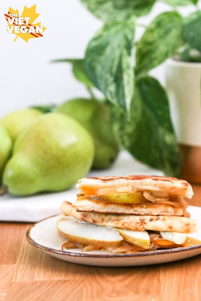 Vegan grilled cheese sandwich with pears and a plant in the background