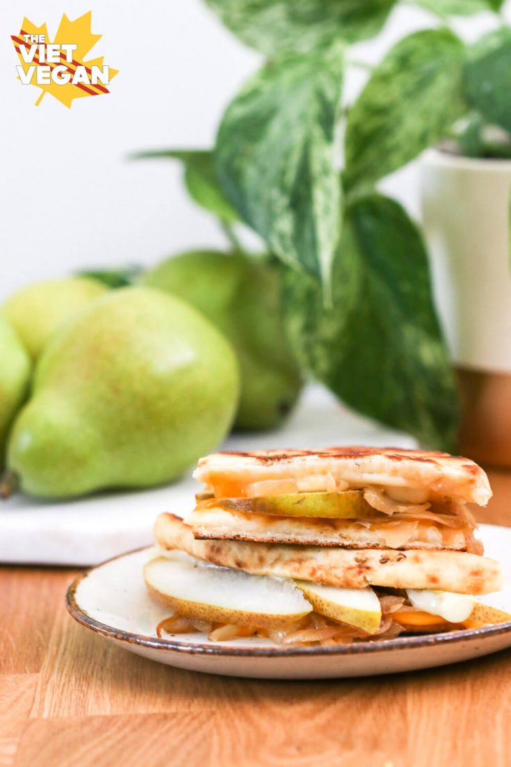 Vegan grilled cheese sandwich with pears and a plant in the background