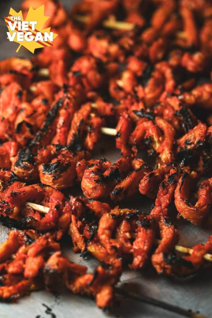 Multiple charred vegan bbq chicken on a skewer on a baking sheet