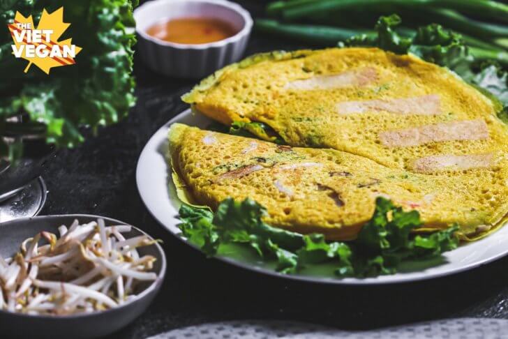 Vegan banh xeo aka Vietnamese pancake on a dish, surrounded by ingredients