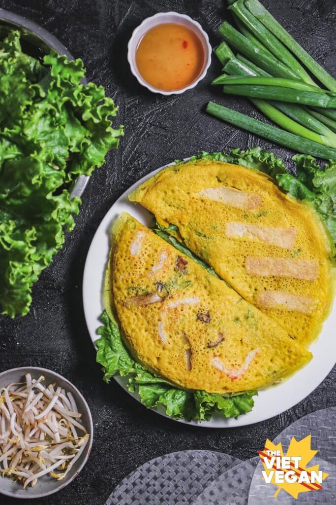 Vegan banh xeo aka Vietnamese pancake on a dish, surrounded by ingredients