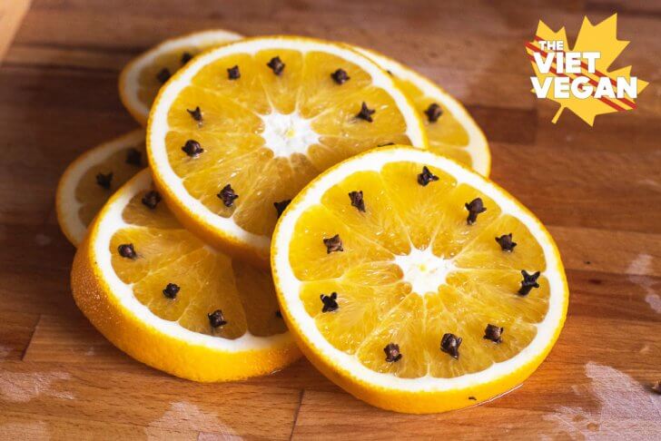 Orange slices pierced with cloves on a cutting board