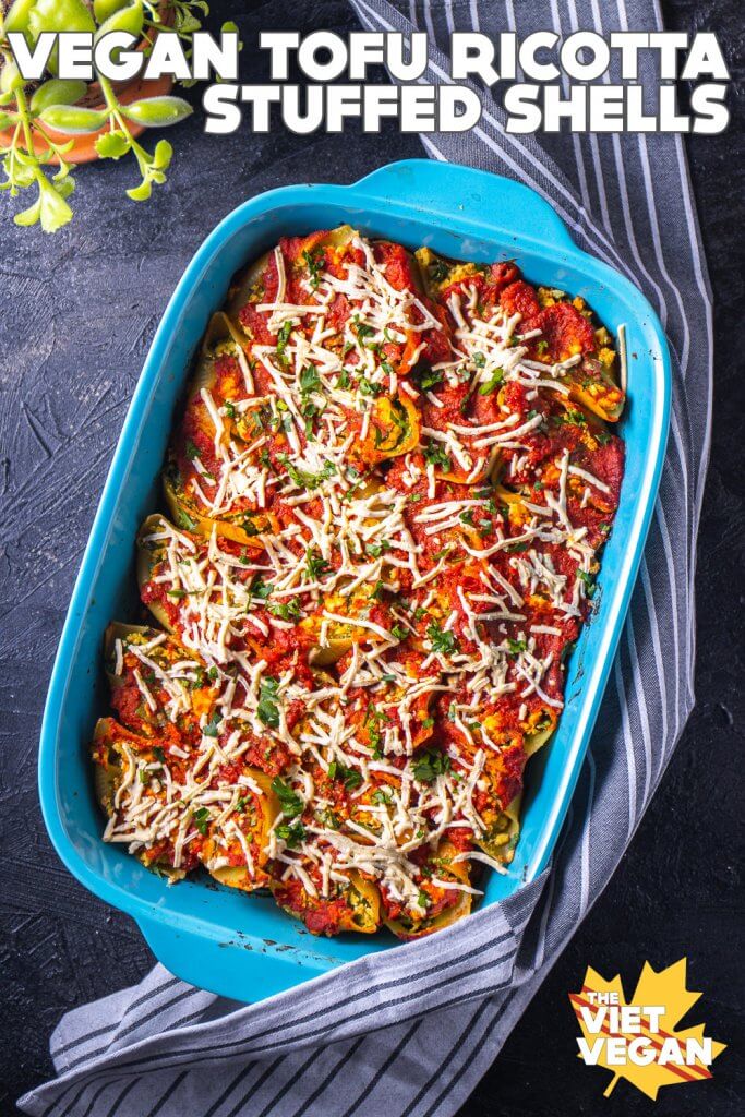 Tofu ricotta stuffed shells in a baking pan topped with sauce and vegan cheese with recipe title