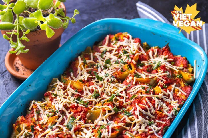 Baked Tofu ricotta stuffed shells in a baking pan topped with sauce and vegan cheese