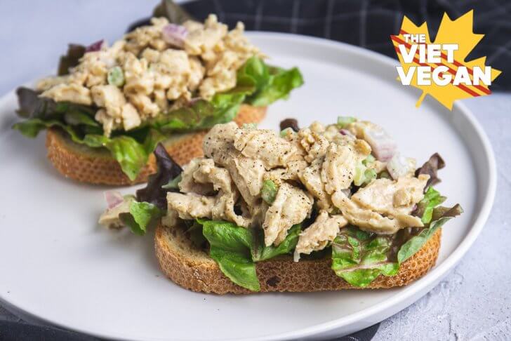 Two vegan chicken salad open faced sandwiches, on a plate with a napkin close up