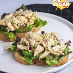 Two vegan chicken salad open faced sandwiches, on a plate with a napkin