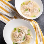 vegan wonton soup in bowls, on a yellow and white kitchen towel, with a spoon, vertical