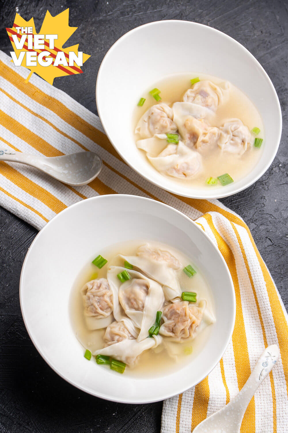 vegan wonton soup in bowls, on a yellow and white kitchen towel, with a spoon, vertical