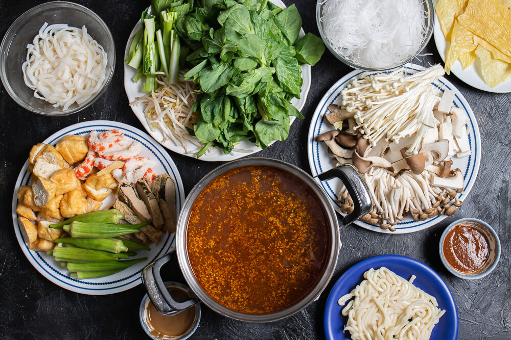 ingredients to put in hot pot on plates surrounding a pot of broth