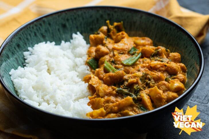 Close up of bowl filled with half curry, half rice, on a yellow napkin on a dark textured surface