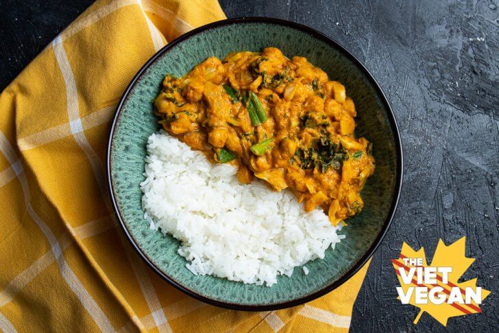 A bowl filled with half curry, half rice, on a yellow napkin on a dark textured surface, horizontal shot