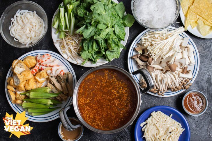 a pot of broth surrounded by ingredients on plates