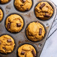 baked muffins in a baking pan on a cooling rack, on a white surface