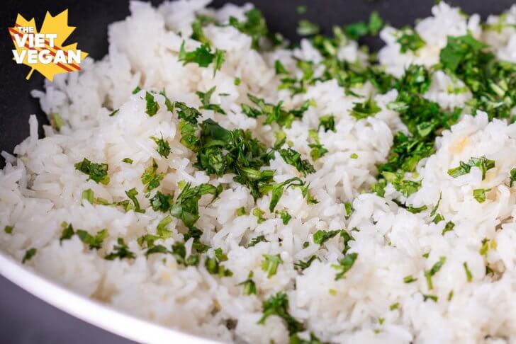 cooked rice in a pan with cilantro on top before mixing in