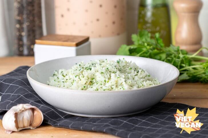 finished cilantro rice in a bowl on a tea towel with cilantro and garlic