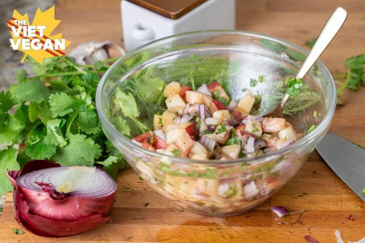 peach salsa mixed in a bowl, surrounded by cilantro, onion, salt on a cutting board