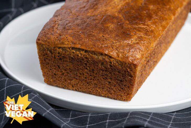 Whole loaf of sourdough banana bread, on a white platter