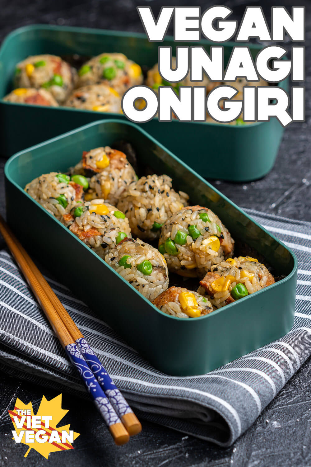Vegan unagi onigiri in a bento box on top of a napkin, with another layer of onigiri behind