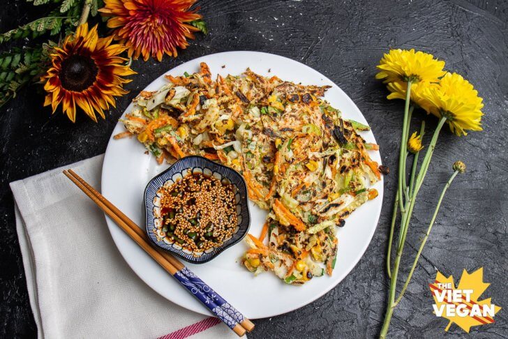 Vegan vegetable fritters on a plate with dipping sauce, surrounded by autumn flowers (dahlias)