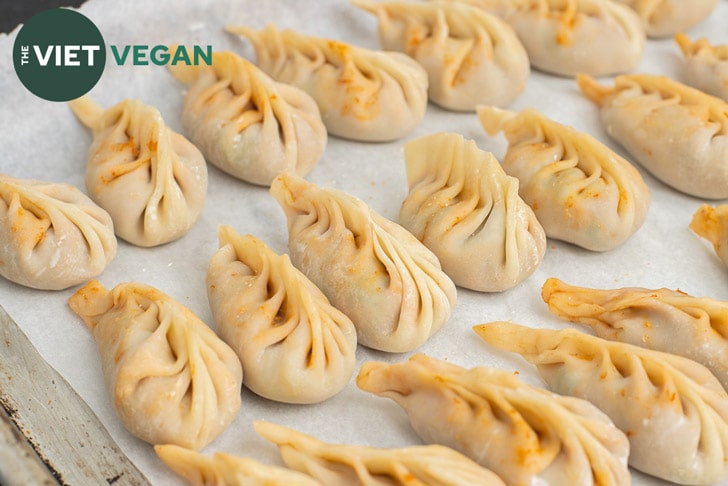 a dozen or so braided dumplings, uncooked, on a parchment paper lined baking sheet