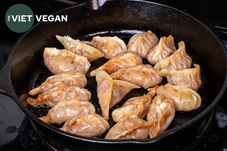 red curry braided dumplings steam frying in a cast iron pan