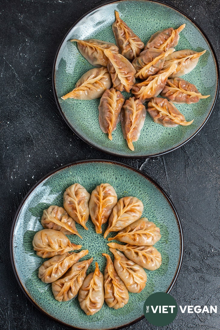 two plates of red curry braided dumplings, one is steamed, one is steam fried