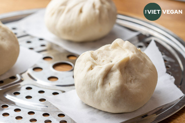 bao buns on parchment paper squares, ready to be steamed