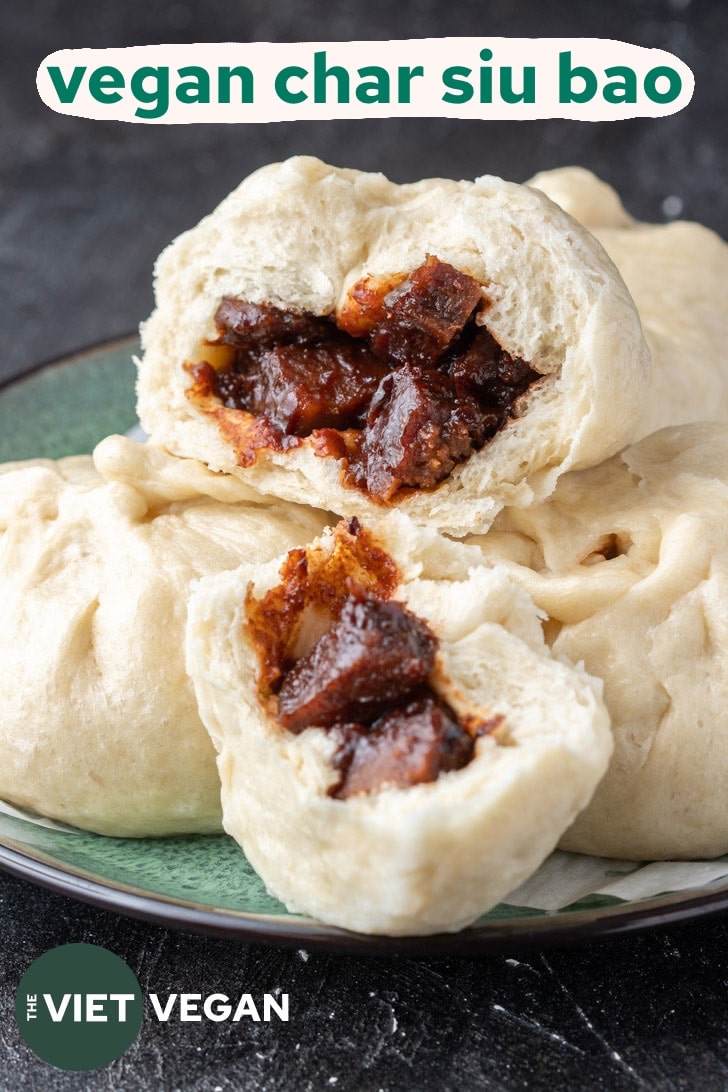 A plate of vegan char siu bao buns with one split open to reveal the char siu seitan inside