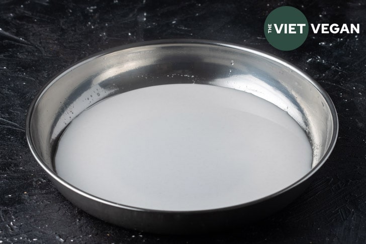 wheat starch noodle batter in a stainless steel non-stick pan to be steamed