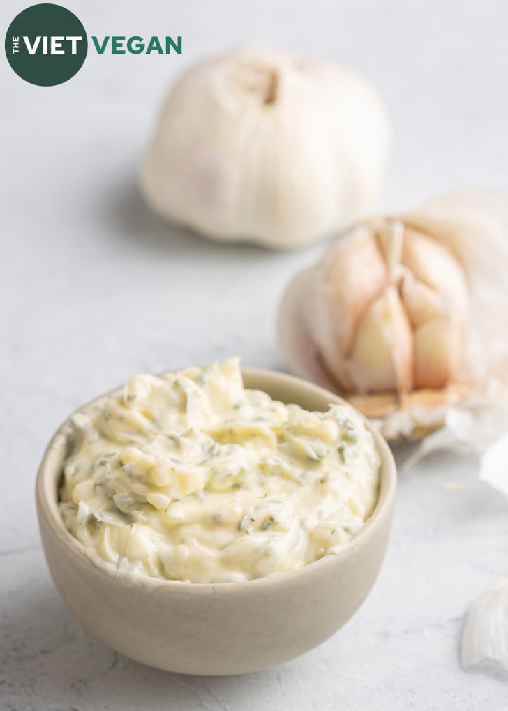 garlic butter in a small bowl, with a full head of garlic and a half head in the background