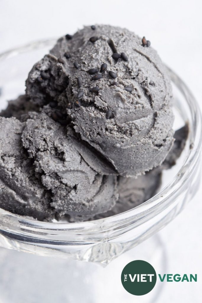 A close up shot of three scoops of black sesame ice cream in a cup.