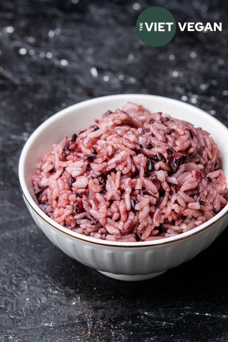 purple rice in a small rice bowl, off center on a dark background