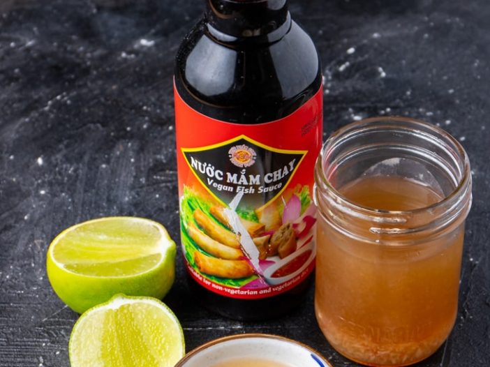 nuoc cham with vegan fish sauce bottle, surrounded by lime, garlic, and chili pepper