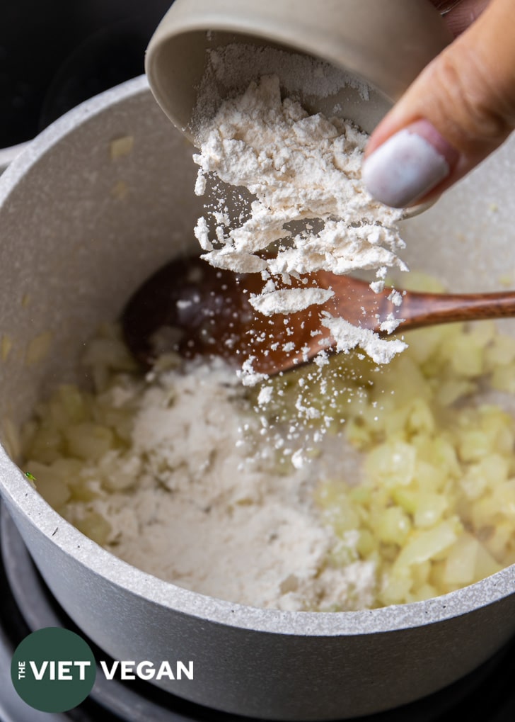 adding flour to onions and garlic to make roux