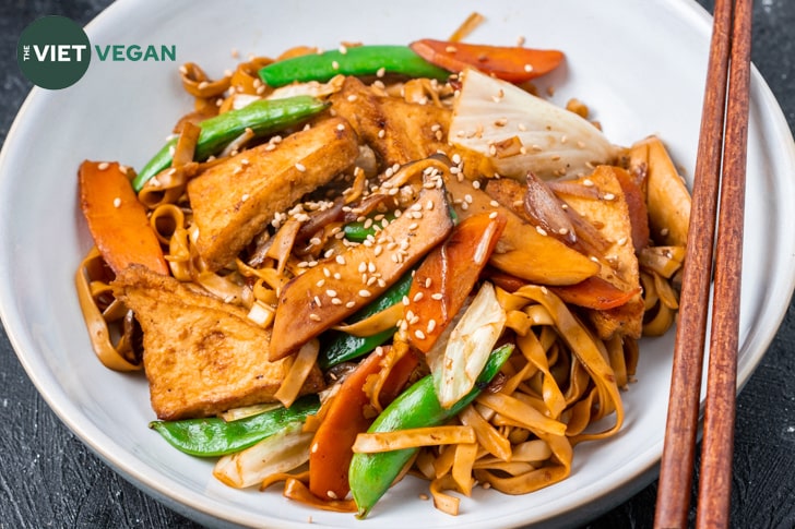 chow mein stir fried with vegetables in a white bowl on a dark background