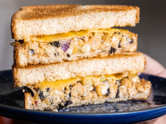 chickpea tuna melt cut in half and stacked on a blue speckled plate