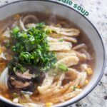 vegan udon noodle soup with toppings in a bowl on a granite countertop