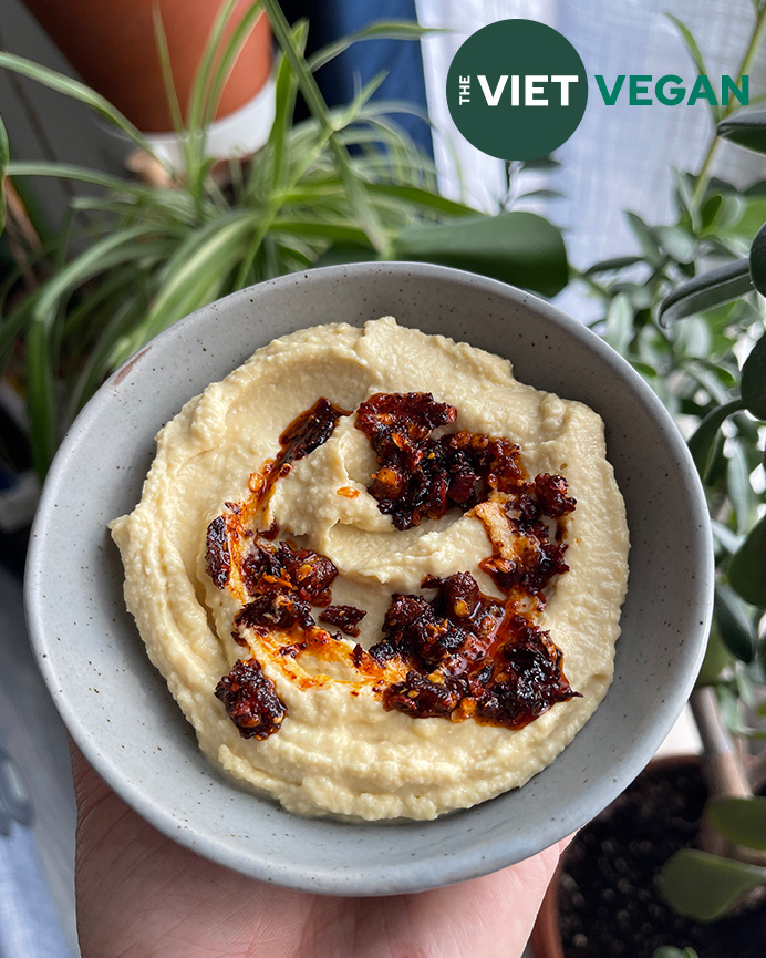 The creamiest hummus in a serving bowl with chili crisp on top