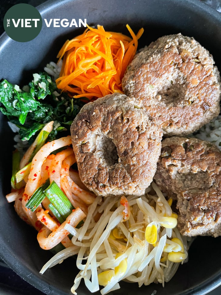 Mini tofu hamburger steaks in a dolsot with other toppings and rice for bibimbap