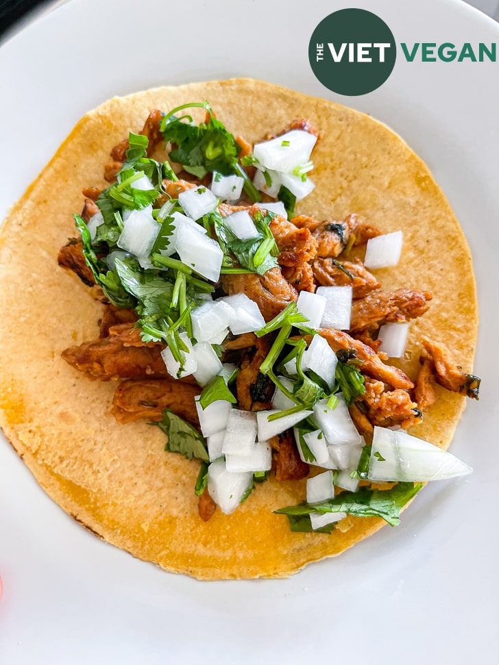 carne asada tacos made with soy curls on a yellow corn tortilla topped with onion cilantro relish