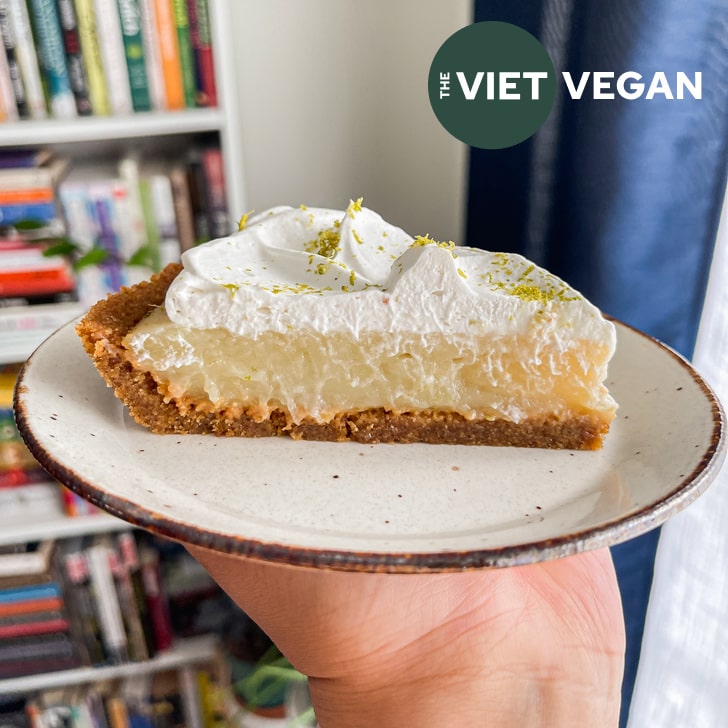 slice of vegan key lime pie on a small plate in front of a bookshelf