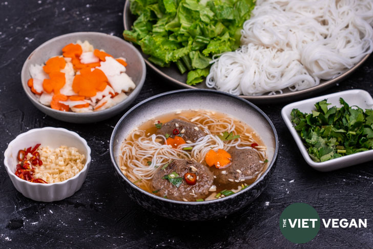 bun cha bowl surrounded by extra toppings in separate dishes