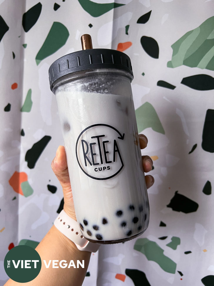 taro milk bubble tea in a large reuseable glass cup over a terrazzo background