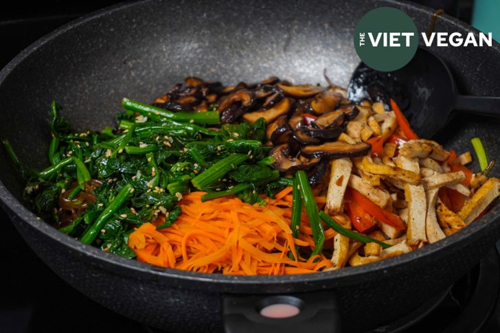 all separate ingredients for japchae on top of a bed of cooked sweet potato vermicelli noodles