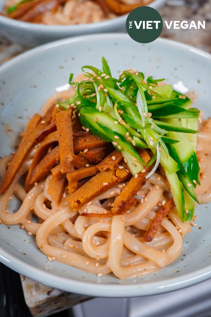 sesame udon topped with sliced seitan, cucumber, and green onion curls