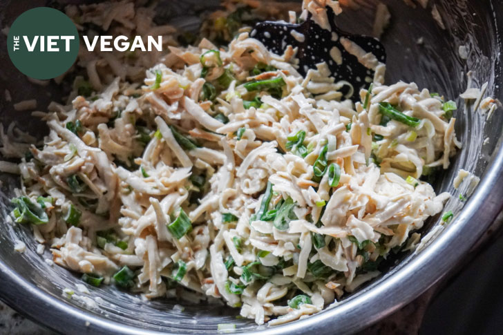 grated smoked tofu in a bowl in a creamy dressing with scallions