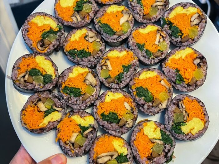 vegan kimbap made with purple rice arranged on a white plate