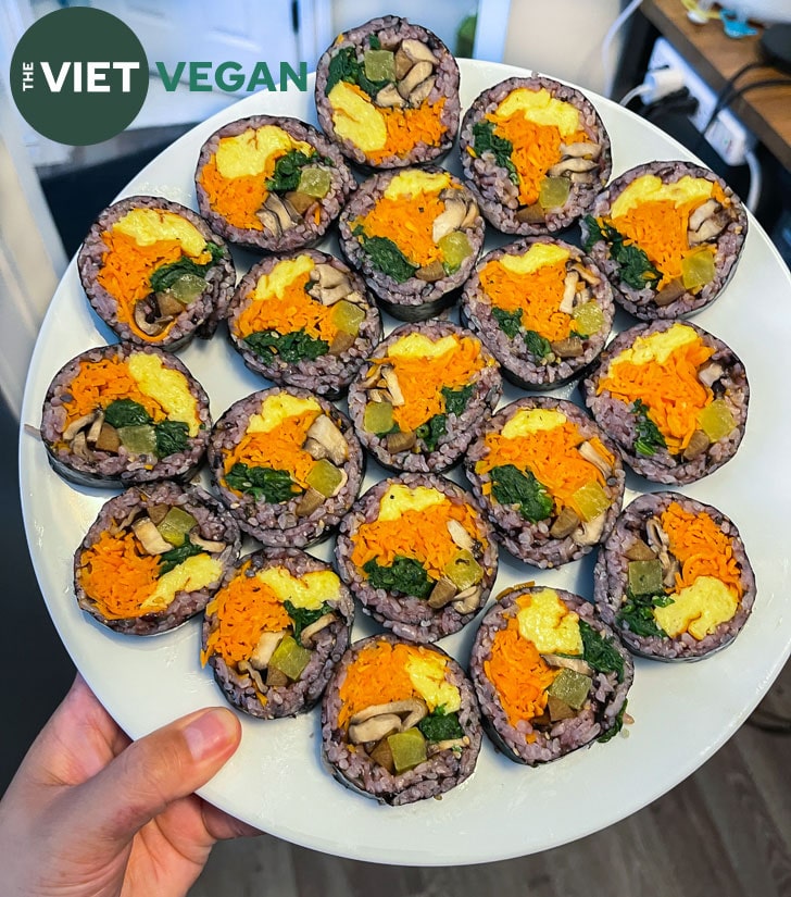 vegan kimbap made with purple rice arranged on a white plate