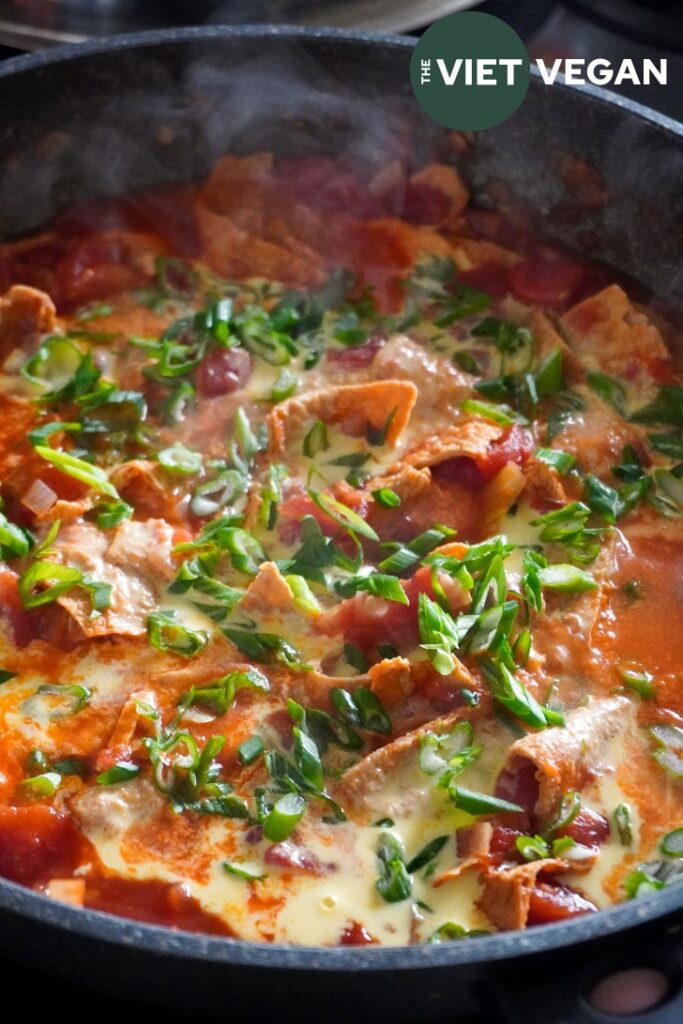 vegan tomato egg in a large wok made with fried bean curd and topped with scallions